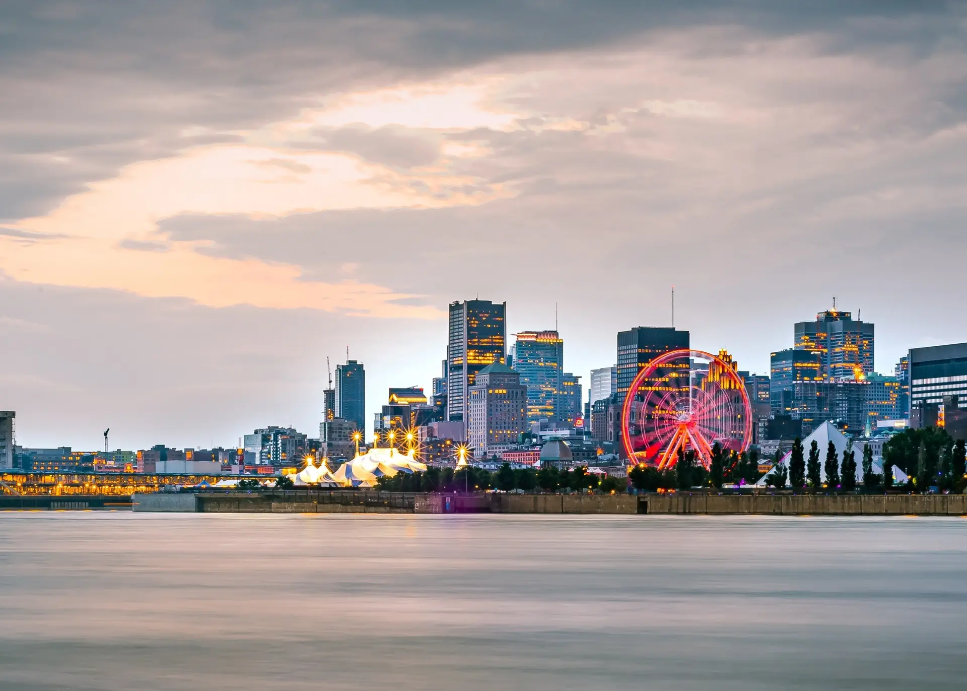 The Montreal skyline and the Old Port Ferris wheel at dusk across the St. Lawrence River, for Sylvie di Giusto, international keynote speaker in Montreal